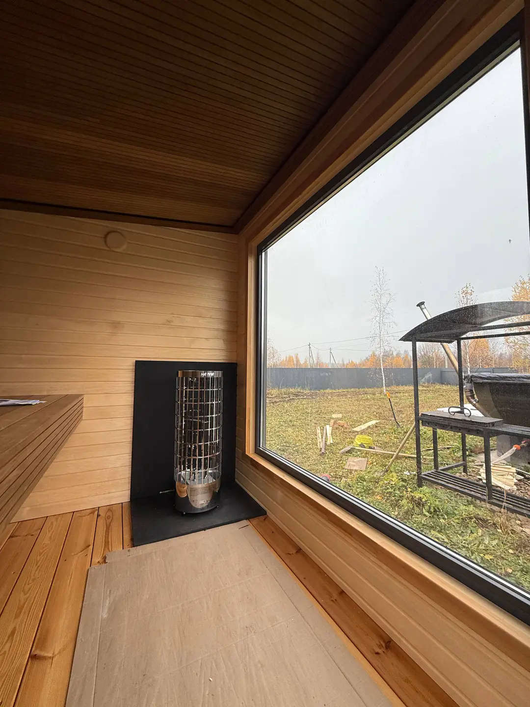Sauna obložena drvetom, sa peći i velikim prozorom